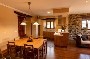 Un comedor y una cocina con mesa y sillas de madera. en Vieiro Verde, en Vieiro