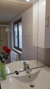 a bathroom with a sink and a vase with a red rose at Ferienwohnung Berndt in Meuselbach-Schwarzmühle