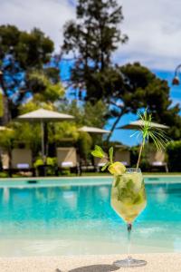 a drink sitting on the sand next to a pool at Leonardo Resort in Imperia