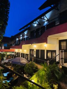- un bâtiment avec une terrasse extérieure avec des parasols la nuit dans l'établissement Détente Hôtel, à Abidjan