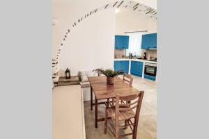 una cucina con tavolo in legno e armadi blu di Kostos House BLUE a Kóstos