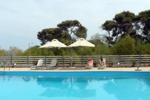 two people sitting under umbrellas next to a swimming pool at Antorina Beachfront Villas in Kamárion