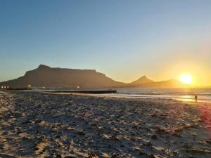 a sunset on a beach with a mountain at Cape Town Beachfront Apartments at Leisure Bay in Cape Town