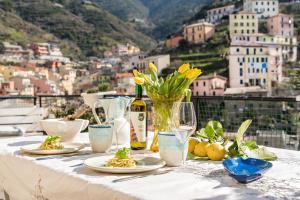 a table with plates of food and a bottle of wine at Villino Caterina House: big terrace seaview in Riomaggiore