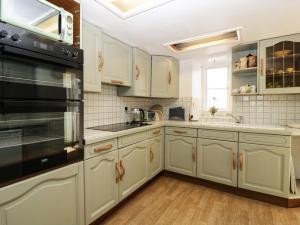 a kitchen with white cabinets and a black appliance at Small Piece in Minehead