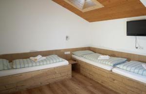 two beds in a room with a flat screen tv at Pension Traube in Uderns