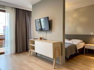 a bedroom with a bed and a television on a dresser at Apartamenty Bałtyckie - Wczasowa - osiedle zamknięte, winda, miejsce parkingowe in Ustka