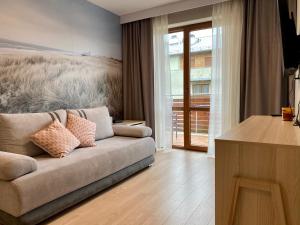 a living room with a couch in front of a window at Apartamenty Bałtyckie - Wczasowa - osiedle zamknięte, winda, miejsce parkingowe in Ustka