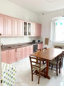 eine Küche mit rosa Schränken und einem Holztisch in der Unterkunft Casa Ada in Marina di Cecina