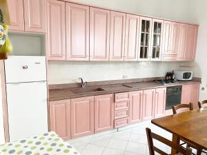une cuisine avec des placards roses et une table dans l'établissement Casa Ada a Marina di Cecina by Zoom In Earth, à Marina di Cecina 15 autres photos