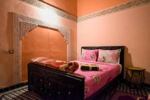 a bedroom with a bed in a room with pink walls at Riad Malak in Fez