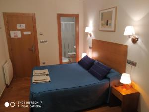 Habitación pequeña con cama azul y baño. en Hotel Sol de la Blanca en Cudillero