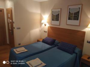 um quarto com 2 camas com lençóis e almofadas azuis em Hotel Sol de la Blanca em Cudillero