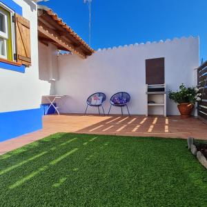 a patio with two chairs and a table and grass at Casa Blanca in Odeceixe