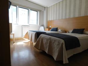 deux lits dans une chambre avec deux fenêtres dans l'établissement Hostal Crisol X Liste Station, à La Corogne
