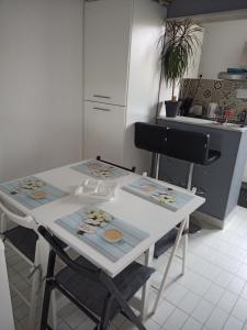 a kitchen with a white table and two chairs at Grand studio au Grau-du-Roi proche Seaquarium et plage in Le Grau-du-Roi