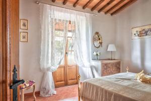 een slaapkamer met een bed en een raam met gordijnen bij Villa Il Cipresso in Sinalunga