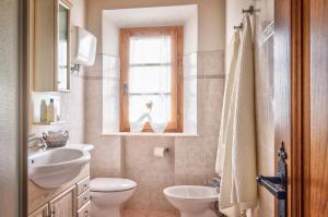 een badkamer met een wastafel, een toilet en een raam bij Villa Il Cipresso in Sinalunga