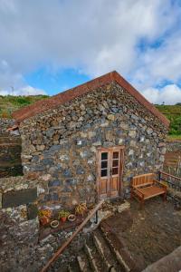 un edificio de piedra con una puerta de madera y un banco en Casita Pedro González, en Erese