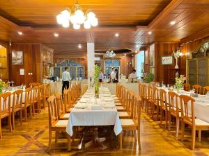 a dining room with tables and chairs and people in the kitchen at E-outfitting Golden Country Hotel in Mandalay