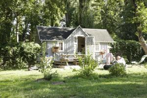 una mujer sentada frente a una casa pequeña en Camping Ile de Boulancourt en Boulancourt