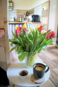 wazon kwiatów na stole z filiżanką kawy w obiekcie Łosiowate Gospodarstwo Agroturystyczne w mieście Rybaki