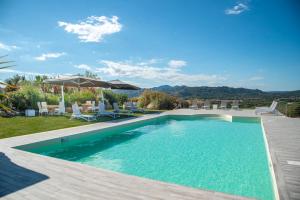 a swimming pool in a yard with chairs and an umbrella at Sacuba Resort & Botanic Golf Club in Olbia