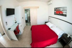 1 dormitorio con cama roja y escritorio en Exotic B&B, en Porto Cesareo
