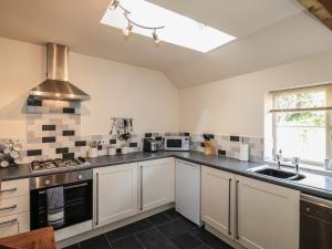 a large kitchen with white cabinets and a sink at Chestnuts Barn in Belper