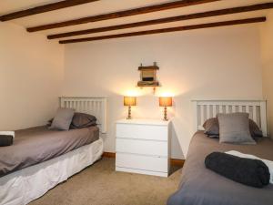 a bedroom with two beds and a white dresser at Chestnuts Barn in Belper