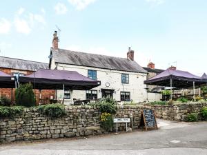 a building with purple umbrellas next to a stone wall at Chestnuts Barn in Belper