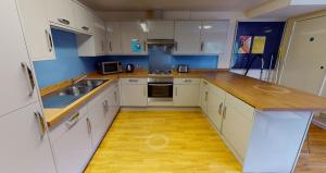 eine Küche mit weißen Schränken und einer hölzernen Arbeitsplatte in der Unterkunft Phoenix Halls in Brighton & Hove