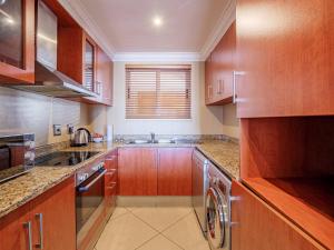 a kitchen with wooden cabinets and a sink and a dishwasher at The Sails G6-07 on Timeball Boulevard in Durban