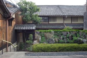 a garden in front of a house with a fence at Demizu Machiya Machiya Inn in Kyoto