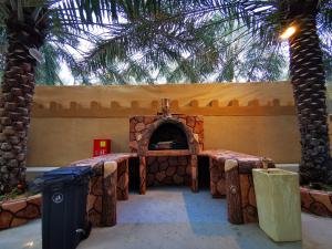 a patio with a pizza oven with palm trees at ALBERI LODGE in Hatta