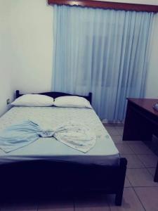 Schlafzimmer mit einem Bett mit blauen Vorhängen und einem Schreibtisch in der Unterkunft Darius Apartment in Sarandë