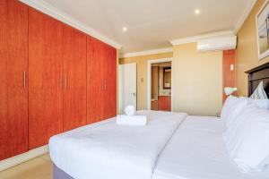 a bedroom with two white beds and wooden cabinets at The Sails G6-07 on Timeball Boulevard in Durban +10 photos