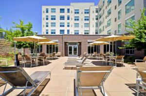 um pátio com mesas, cadeiras e guarda-sóis em Hyatt House Atlanta Cobb Galleria em Atlanta