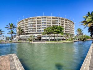 a building with palm trees in front of a body of water at The Sails G6-07 on Timeball Boulevard in Durban