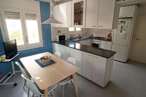 a kitchen with white cabinets and a wooden table with chairs at Ca la Mercè - Agradable casa en Amer in Amer