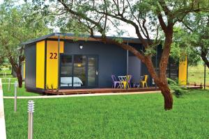 a tiny house with a yellow and blue exterior at SleepOver Komatipoort in Komatipoort