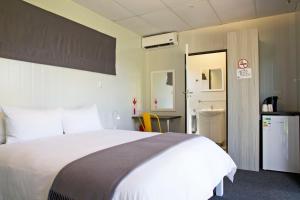 a bedroom with a large white bed and a bathroom at SleepOver Komatipoort in Komatipoort