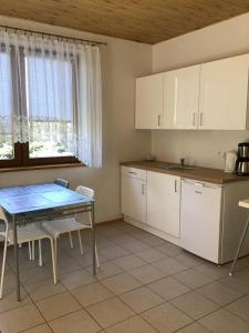 a kitchen with white cabinets and a table with chairs at Agroturystyka Krajno - Zagórze in Krajno-Zagórze