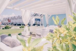 un patio blanco con sillas blancas y dosel blanco en Zatoka Slonca - Domki z basenem, WiFi i parking w cenie! en Mielno