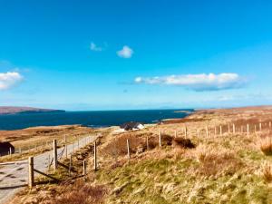 a fence on a hill with the ocean in the background at Coral Cabins in Dunvegan
