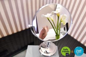 a mirror on a counter with a vase of flowers at Prezident Hotel in Novi Sad