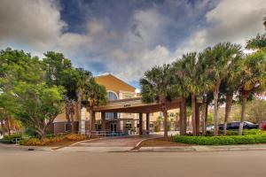 a building with palm trees in front of a street at Holiday Inn Express West Palm Beach Metrocentre, an IHG Hotel in West Palm Beach