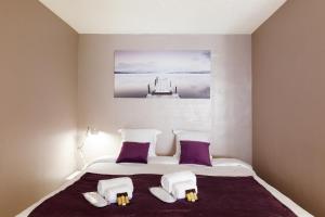 1 dormitorio con 1 cama con almohadas moradas y blancas en Antares S YourHostHelper, en Cannes