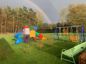 a playground with a rainbow in the background at Apartamenty Gajówka- rowery, plac zabaw, sauna, jacuzzi in Stegna