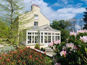 uma casa com um jardim de Inverno com flores cor-de-rosa em Larchmount House B&B em Derry Londonderry